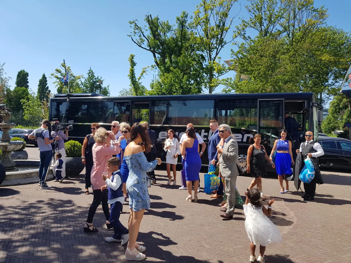 Bruiloftsgasten stappen in de bus