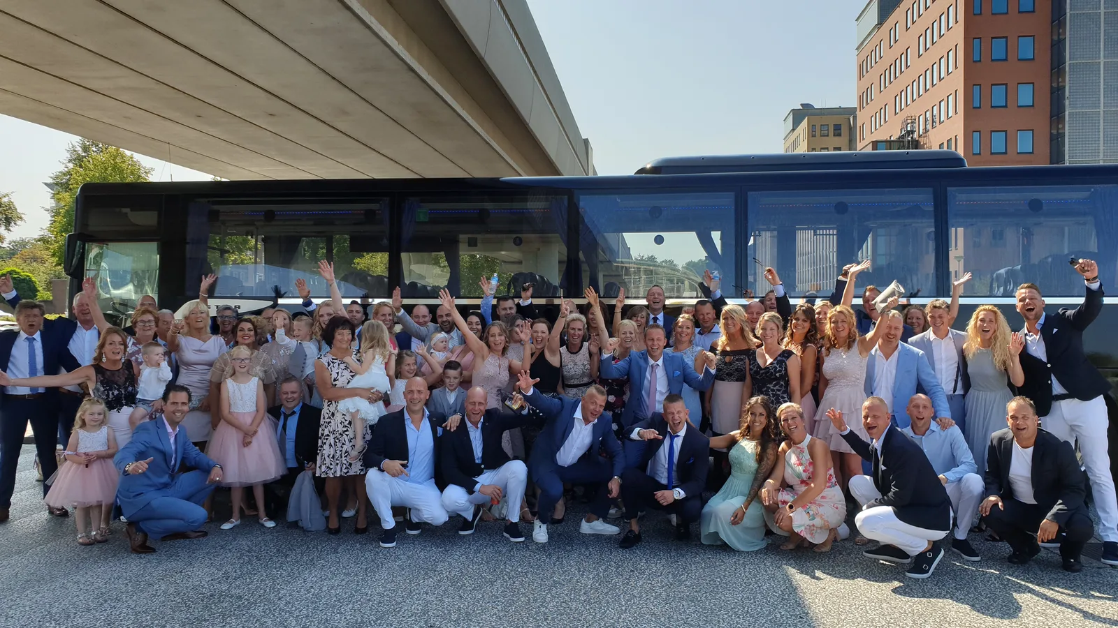 Bruiloftsgezelschap bij de bus